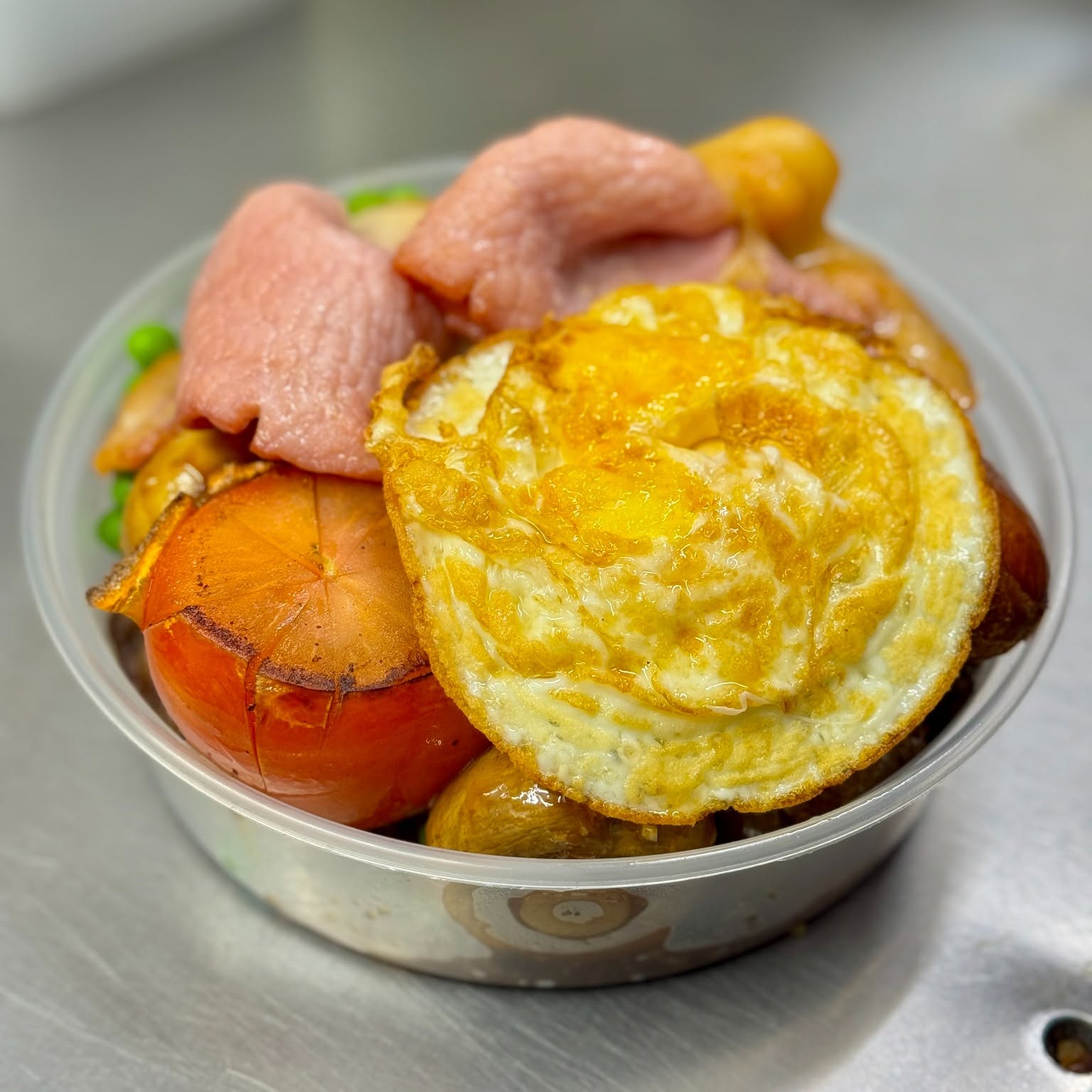 Mixed grill served with fried egg, tomato and peas